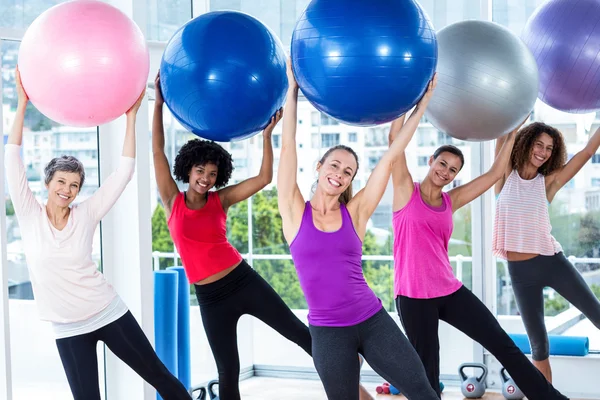 Portret van lachende vrouwen houden oefening ballen met armen verhogen — Stockfoto