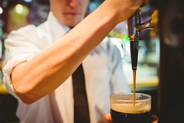 Cantinero sosteniendo vaso de cerveza debajo del grifo del dispensador —  Fotos de Stock