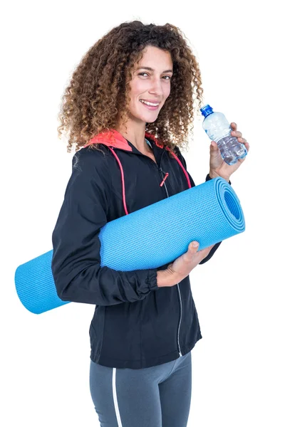 Jovem segurando garrafa de água e tapete de exercício — Fotografia de Stock