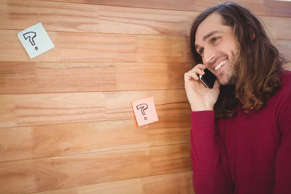 Hombre feliz usando el teléfono móvil apoyado en la pared de madera — Foto de Stock