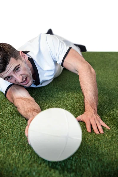 Hombre sosteniendo pelota de rugby mientras se acuesta — Foto de Stock