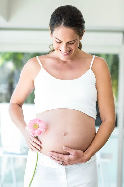 Gelukkige vrouw bedrijf flower door buik — Stockfoto