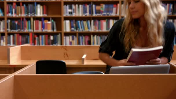 Student som arbeider med bærbar datamaskin i biblioteket – stockvideo