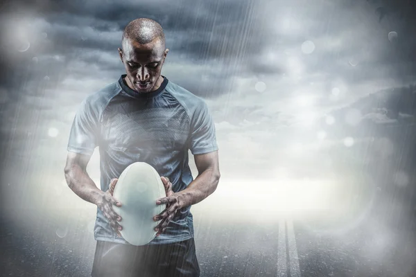 Doordachte atleet kijken naar rugbybal — Stockfoto