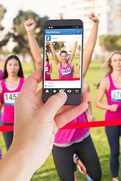 Imagen compuesta de la mano femenina sosteniendo un smartphone — Foto de Stock