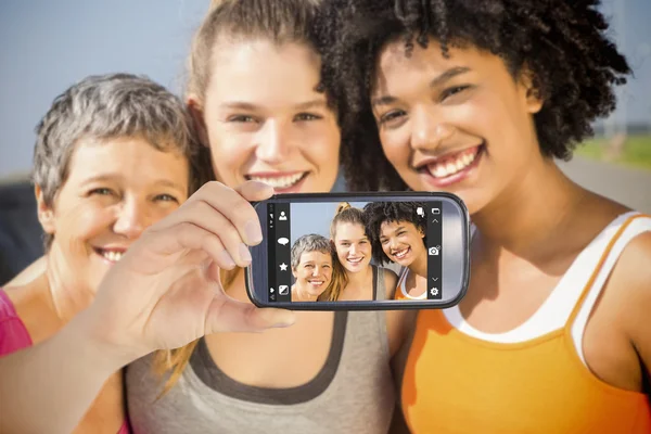 Smartphone showing sporty women — Stock Photo, Image