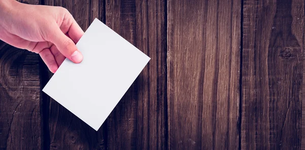 Hand holding paper against wooden wall — Stock Photo, Image