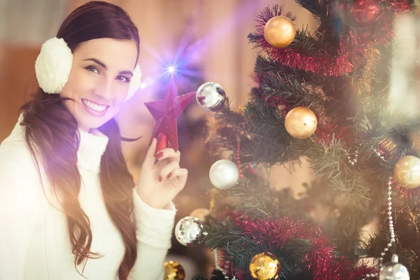 Sonriente morena sosteniendo estrella cerca de un árbol de navidad —  Fotos de Stock