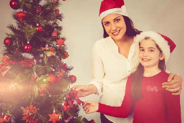 Mutter und Tochter hängen Weihnachtsschmuck an Baum — Stockfoto