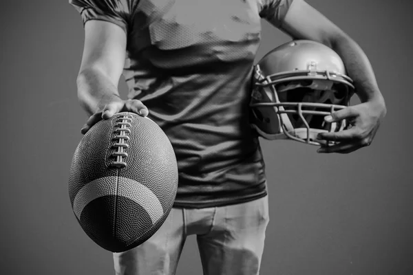 Deportista mostrando fútbol americano mientras sostiene el casco — Foto de Stock