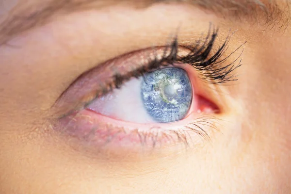 Nahaufnahme eines weiblichen blauen Auges gegen die Erde — Stockfoto