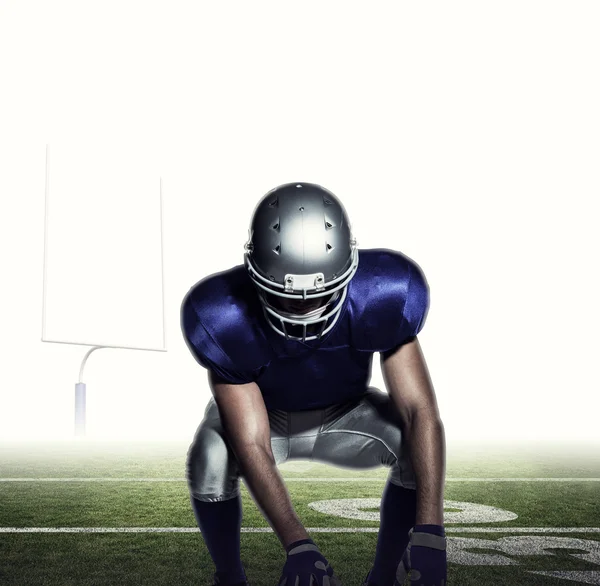 American football player holding ball while crouching — Stock Photo, Image