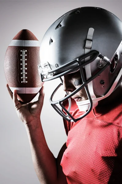 Sportler schaut nach unten, während er American Football hält — Stockfoto