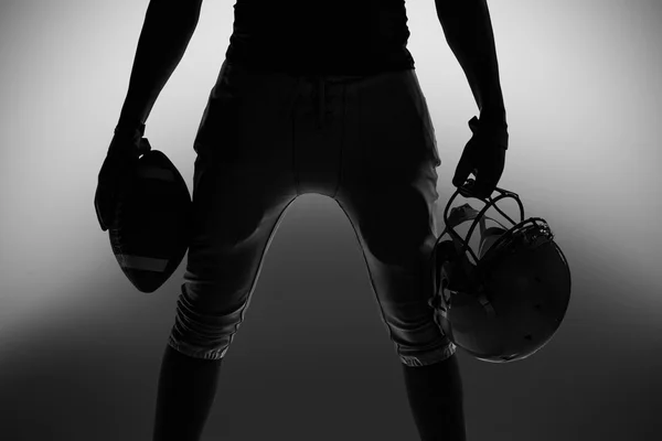 Silhouette of sportsman holding ball and helmet — Stock Photo, Image