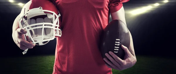 Jugador de fútbol americano sosteniendo un casco y una pelota — Foto de Stock
