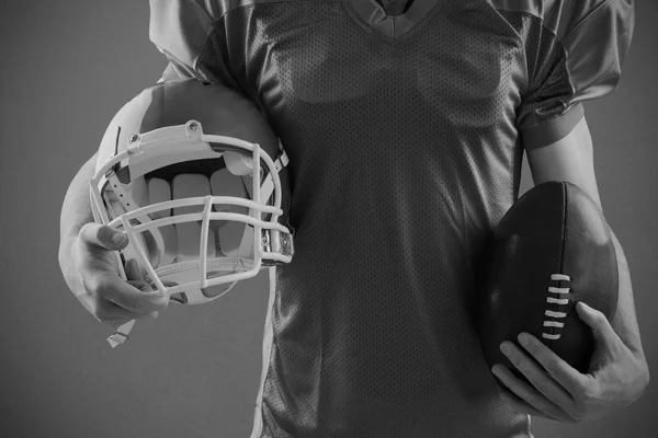 Jugador de fútbol americano sosteniendo un casco y una pelota — Foto de Stock