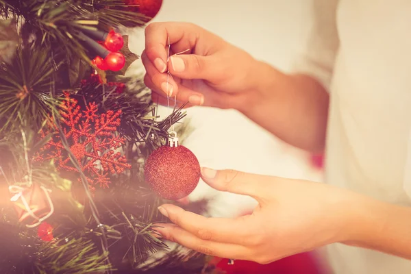 Frau hängt Weihnachtsschmuck an Baum — Stockfoto