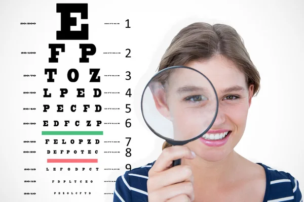 Woman holding magnifying glass against eye test — Stock Photo, Image