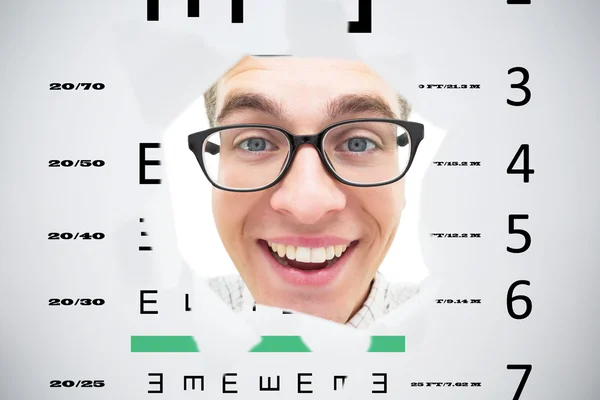 Geeky hipster smiling through hole against eye test — Stock Photo, Image