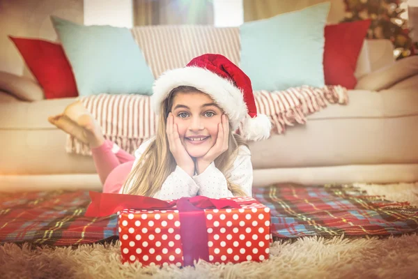 Festliches kleines Mädchen lächelt mit Geschenk in die Kamera — Stockfoto