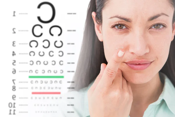 Morena sosteniendo lente de contacto contra la prueba ocular — Foto de Stock