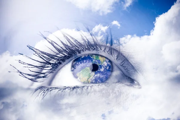 Женский голубой глаз против голубого неба с облаками — стоковое фото