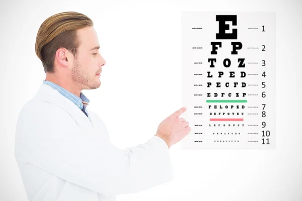 Composite image of optician in coat pointing eye test — Stock Photo, Image