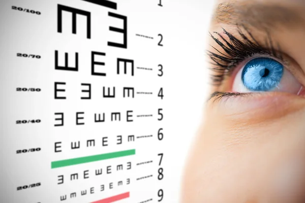 Eye looking up on female face against eye test — Stock Photo, Image