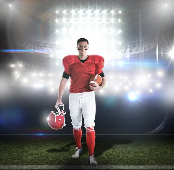 Jugador de fútbol americano caminando y sosteniendo el fútbol y el casco — Foto de Stock
