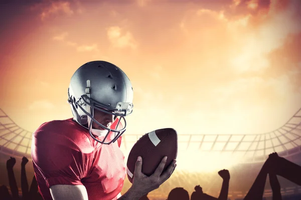 Sportsman looking at american football with cheering crowd — Stock Photo, Image