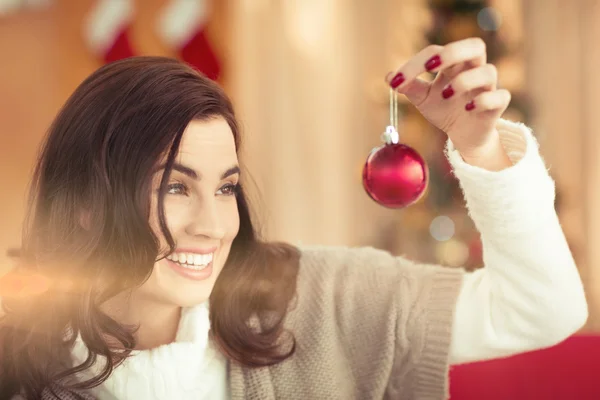 Sorrindo morena segurando uma bugiganga no Natal — Fotografia de Stock