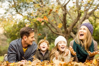 Smiling young family throwing leaves around clipart