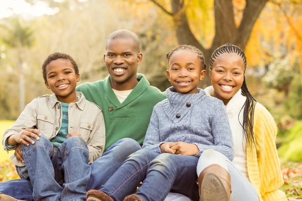 Porträt einer jungen Familie, die in Blättern sitzt — Stockfoto