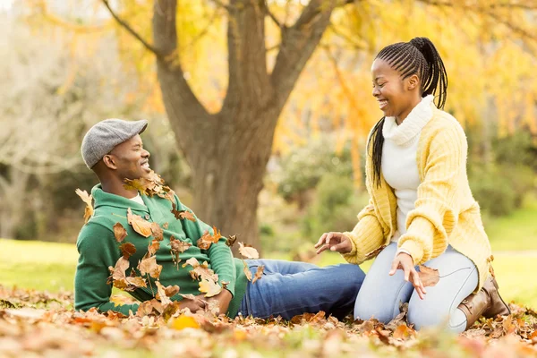 Veduta di una giovane coppia sorridente in foglie — Foto Stock