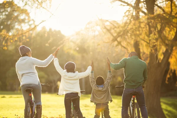 Visão traseira de uma jovem família com braços levantados na bicicleta — Fotografia de Stock
