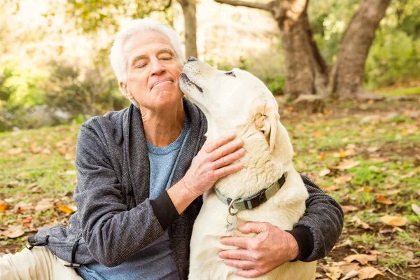 Старший чоловік зі своїм собакою в парку — стокове фото