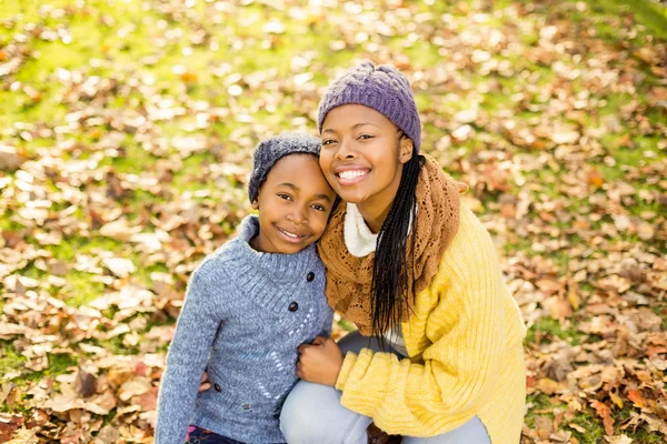 Jovem mãe com sua filha sentada em folhas — Fotografia de Stock