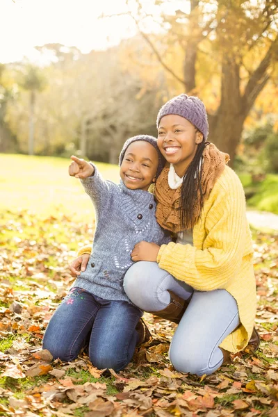 Giovane madre con sua figlia seduta in foglie — Foto Stock