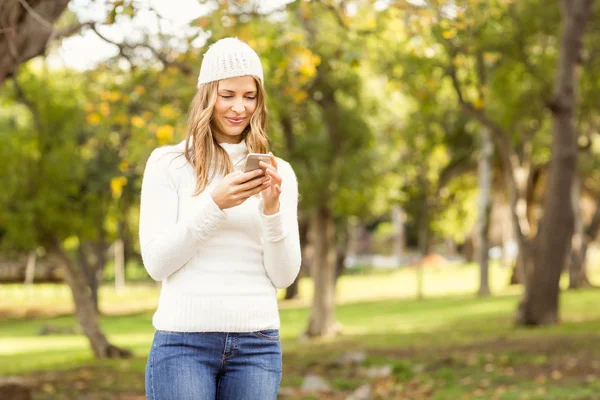 Lächelnde hübsche Frau, die mit ihrem Smartphone SMS schreibt — Stockfoto