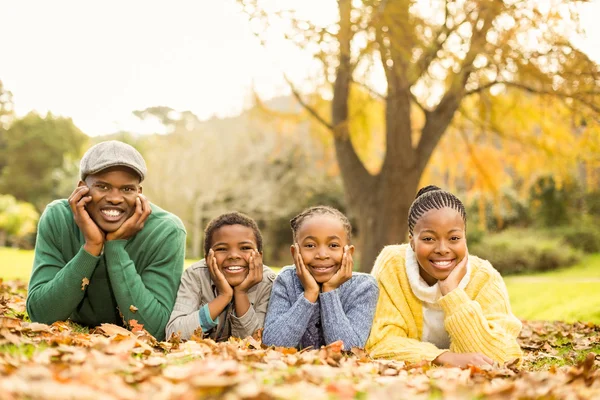 Retrato de una joven familia sonriente acostada en hojas — Foto de Stock