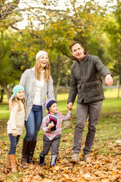 Sorridente giovane famiglia che cammina in foglie — Foto Stock