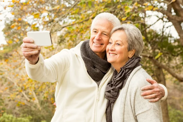 Äldre par i parken med selfie — Stockfoto