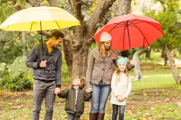 Sorrindo jovem família sob guarda-chuva — Fotografia de Stock