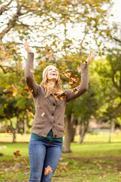 Donna sorridente che lancia foglie in giro — Foto Stock