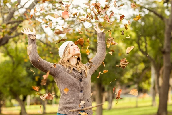 Uśmiechnięta kobieta rzucając liści wokół — Zdjęcie stockowe