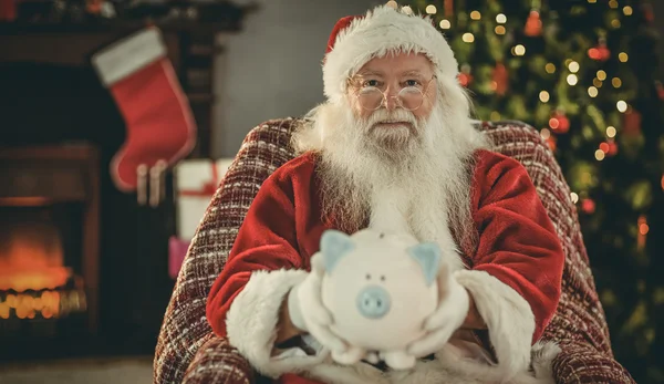 Lächelnder Weihnachtsmann bietet Sparschwein an — Stockfoto