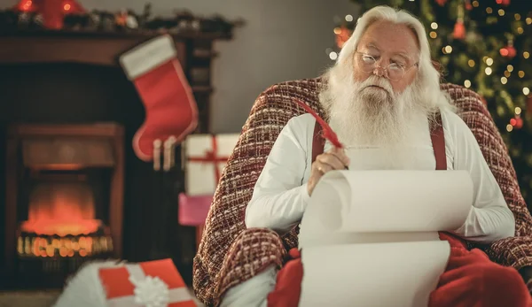 Entspannter Weihnachtsmann schreibt Liste mit Federkiel — Stockfoto