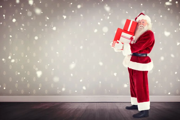 Composite image of santa carrying gifts — Stock Photo, Image