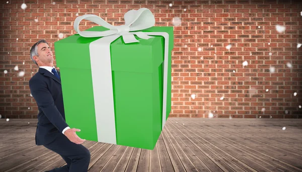 Imagen compuesta de hombre elegante con regalo gigante — Foto de Stock