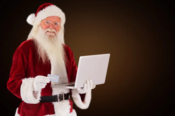 Babbo Natale paga con carta di credito su un portatile — Foto Stock